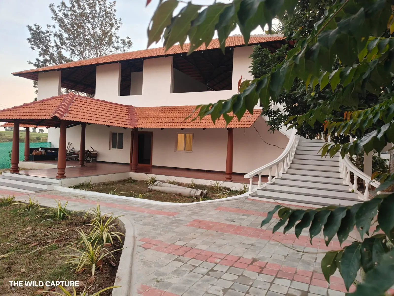 Front of the villa with its Malnad tiled roof, pillared verandah and curved staircase